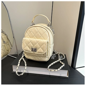 Detailed view of quilted cream mini backpack with silver chain strap and metal clasp
