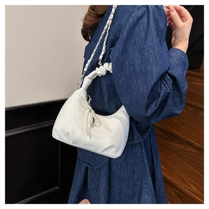 Detail of white pleated patent leather bag with pearl fringe and cloud-style handle