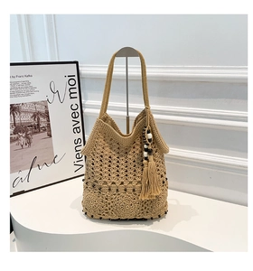 Detail of handmade crochet shoulder bag with intricate cutout patterns and tassel charm