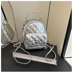 Close-up of silver quilted mini backpack with metal chain strap and twist-lock detail