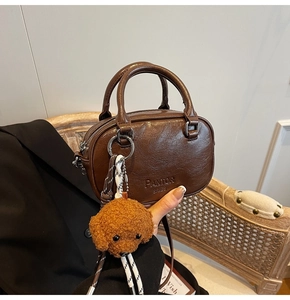 Detail of brown litchi pattern PU leather bag with PANTOR SRIES logo and teddy charm