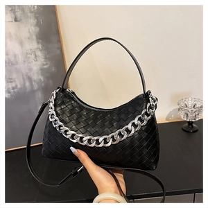 Close-up of black woven leather underarm bag with thick silver chain and adjustable strap