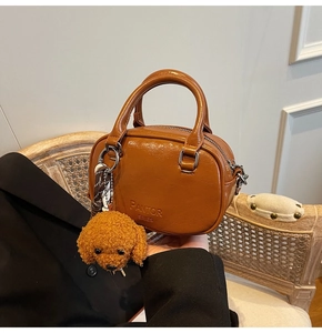 Brown vintage circular bag with metal handles, plush dog charm, and polka dot scarf detail