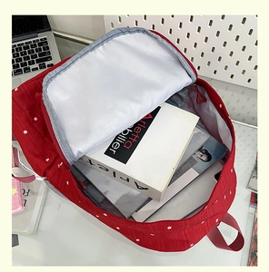 Close-up of red floral backpack showing wide opening and large internal storage capacity