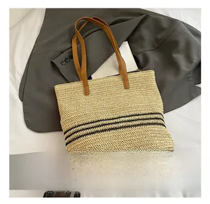 Détail de la texture en paille tressée avec rayures noires et lanières en cuir marron
