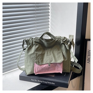 Détail du sac cabas en nylon olive avec poche rose et bandoulière sous une lumière douce