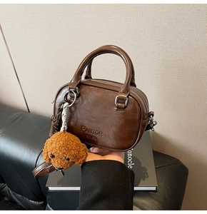 Detail of vintage brown mini bowling bag with a cute plush dog charm and embossed text