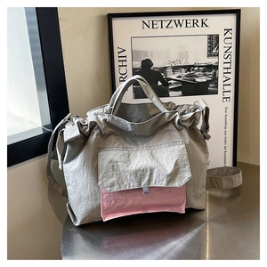 Détail du cabas en nylon gris avec poche rose et bandoulière réglable pour le confort