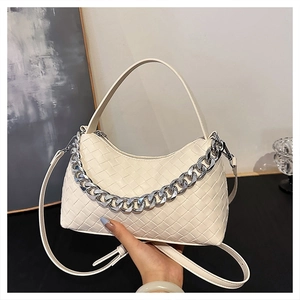 Close-up of cream woven dumpling bag featuring silver chain and intricate texture