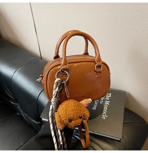 Detailed macro view of brown vintage Boston bag with brand embossing and plush dog charm