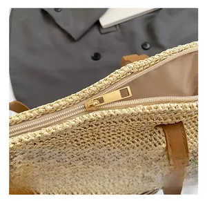 Gros plan sur la fermeture éclair dorée et l'anse en cuir d'un sac cabas en paille tissée