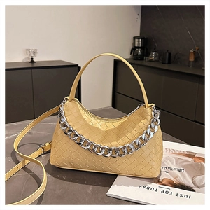 Detail of yellow woven hobo bag featuring silver chain and intricate texture