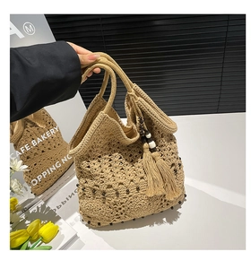 Detail of hand-woven cotton beach bag with boho tassels and beaded decorative elements