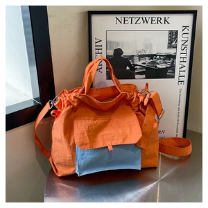 Détail d'un sac cabas en nylon orange vif avec poche bleue contrastée et fermeture à cordon