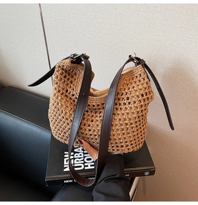 Detail of woven straw shoulder bag featuring high-quality brown leather straps and metal buckle