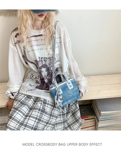 Detail of a denim bucket bag with silver handles and rivet studs on wood background