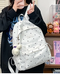 Detailed shot of white polka dot backpack with a cute plush rabbit charm and star pattern