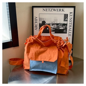 Détail du sac cabas en nylon orange avec poche bleu clair et texture froissée fine
