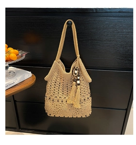 Close-up of crochet hollow pattern with wooden beads and tassel on the woven bag