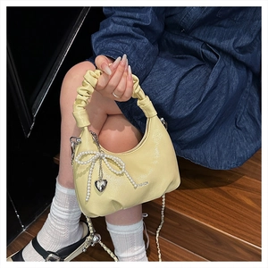 Detail of cream yellow crescent bag with pearl bow charm and ruched cloud handle