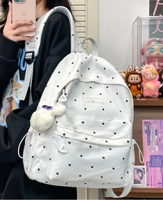 Close-up of white floral backpack with cute plush charm and black polka dot pattern