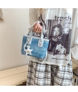 Detail of light blue denim mini bucket bag with silver star pendant and metallic handles