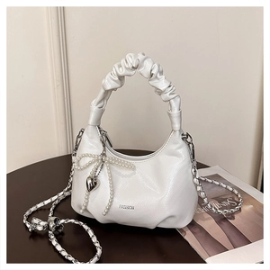 Detail of white pleated handbag with pearl bow, heart charm and silver chain strap
