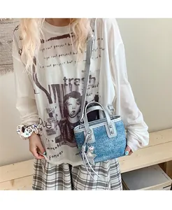 Detail of a mini denim bucket bag featuring silver handles and metallic star charms