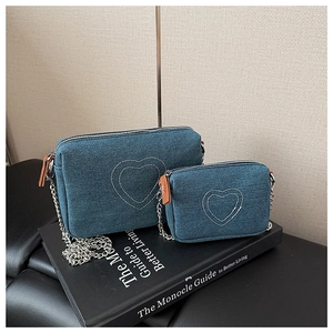 Detail of blue denim heart embroidery pattern and silver metal chain on crossbody bag