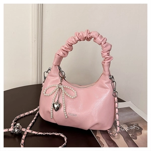 Detailed shot of pink pleated dumpling bag with pearl bow and silver heart pendant