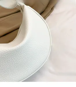 Detailaufnahme einer weißen Halbmond-Tasche mit hochwertiger Lychee-Lederstruktur