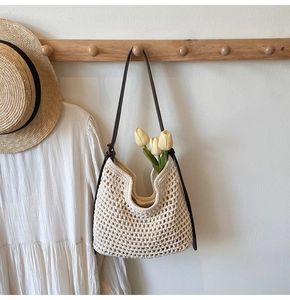 Close-up of cream crochet tote bag with hollow knit texture and brown leather strap
