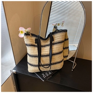 Détail d'un grand sac cabas en paille tissée à rayures noires avec bandoulière en cuir