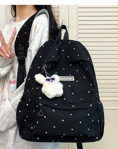 Detailed shot of black floral backpack with cute plush bunny pendant and woven brand label