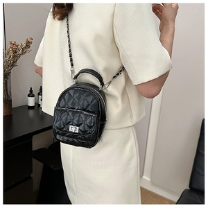 Close-up of black quilted mini backpack with silver chain strap and metal swivel lock detail