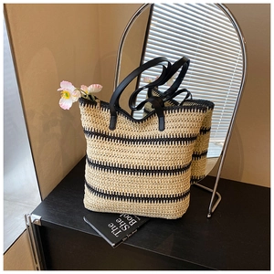 Détail macro du sac cabas en paille avec rayures noires et anses en cuir
