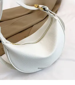 Makro-Detail der weißen Hobo-Tasche aus Leder mit Litschistruktur und Goldreißverschluss