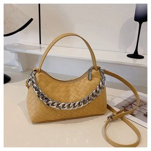 Detail of yellow woven leather dumpling bag with chunky silver chain and handle