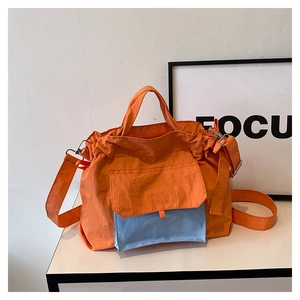 Détail du fourre-tout en nylon orange montrant la poche bleu clair et la bandoulière réglable