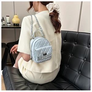 Detail of light blue quilted mini backpack with silver chain strap and metal clasp