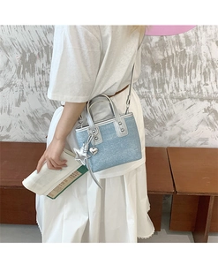 Detail showing blue denim mini bucket bag with silver heart charms and crossbody strap