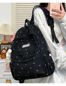 Detail of black floral backpack with white flower patterns and a plush ball charm