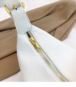 Detailaufnahme des goldenen Metallreißverschlusses an der weißen Umhängetasche aus Leder