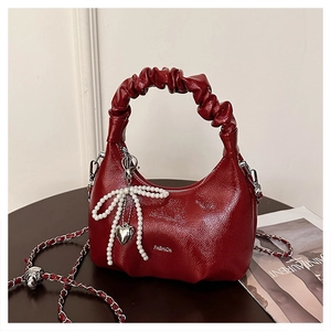 Detail of dark red ruched handbag with pearl bow and silver heart charm pendant