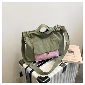 Détail du cabas en nylon vert armée sur valise avec poche contrastée rose et anses