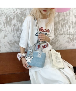 Detail of light blue denim bucket bag with silver star charm and metallic handle
