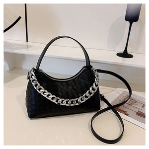 Detail of black woven shoulder bag featuring a chunky silver chain and leather handle
