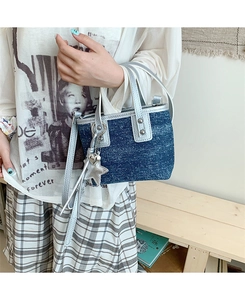Detail of denim bucket bag with silver leather handles and star charm accessory
