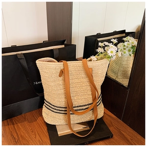 Détails d'un sac cabas en paille tressée avec rayures noires et anses en cuir marron
