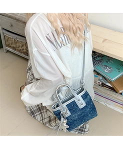 Detail of a dark blue denim bucket bag with silver trim and star charm on a model